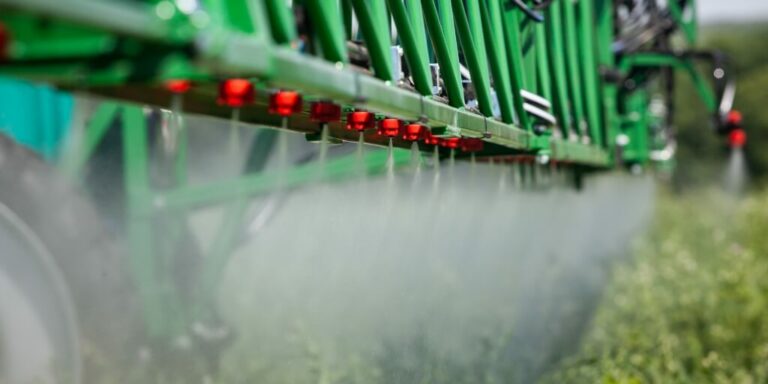 Pulverizador verde aplicando herbicida na lavoura