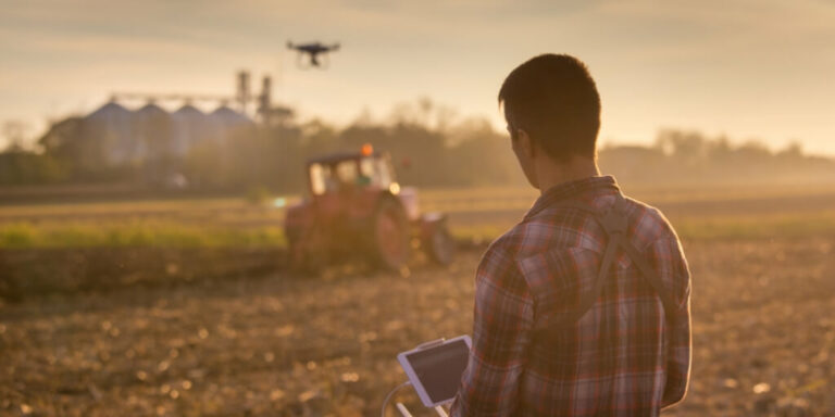 agricultor manejando drone sobre a lavoura e sobre um trator obedecendo as regras para uso de drone na agricultura