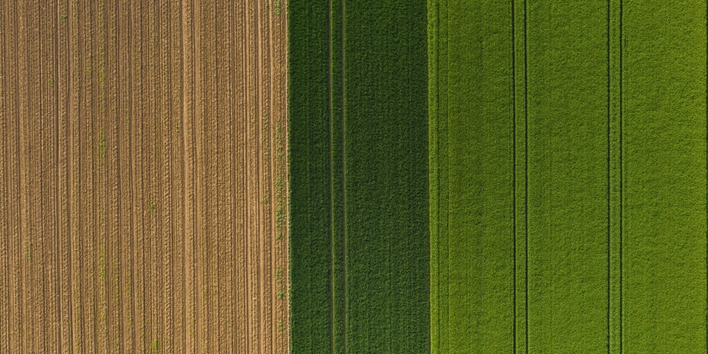 Vista aerea superior de diferentes campos agricolas representando Importancia do geoprocessamento no planejamento rural